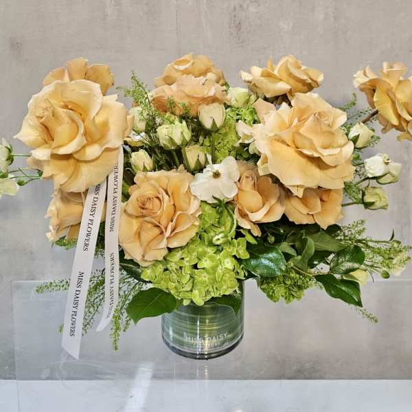 Peach roses and green hydrangeas in a glass vase