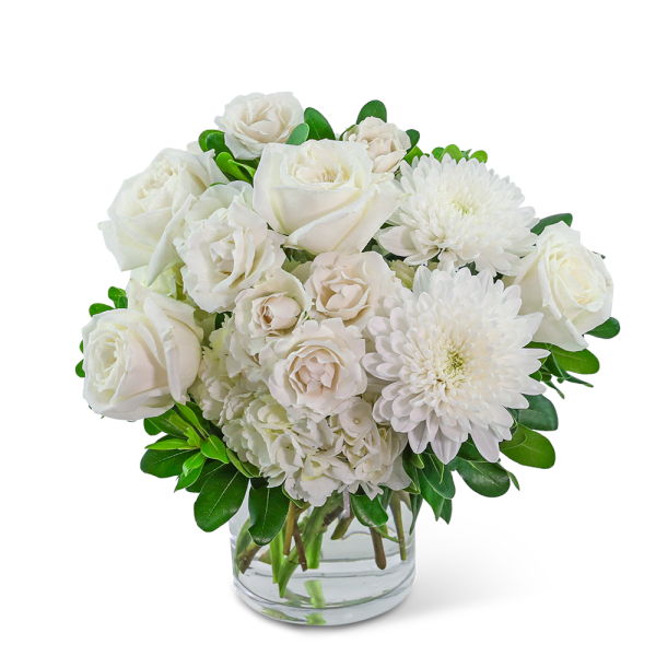 White roses and chrysanthemums arranged in a clear glass vase