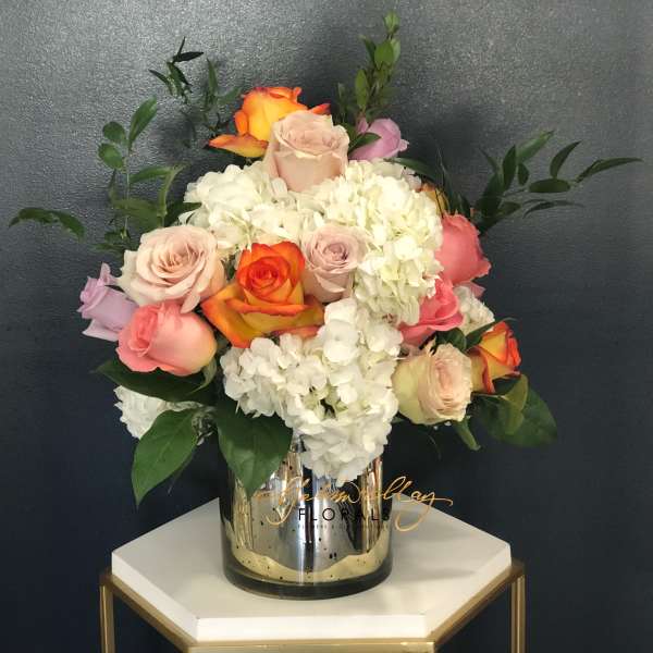 Mixed roses and white hydrangeas in a mirrored vase