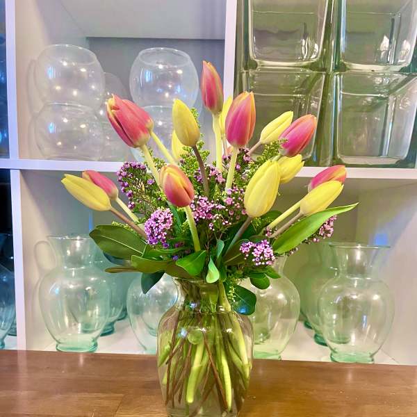 Pink and yellow tulips arranged in a clear glass vase