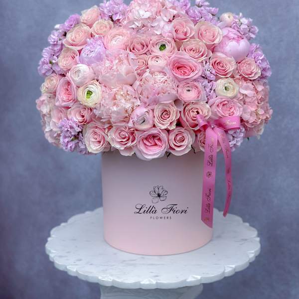 Pink rose and hydrangea arrangement in a round hat box with ribbon