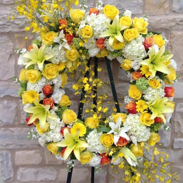 Yellow and white floral wreath on a black stand