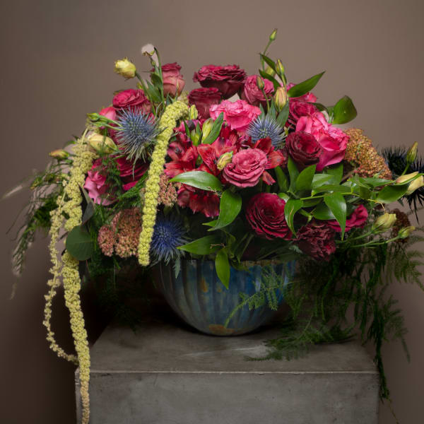 Large mixed bouquet of pink and burgundy flowers in a blue vase