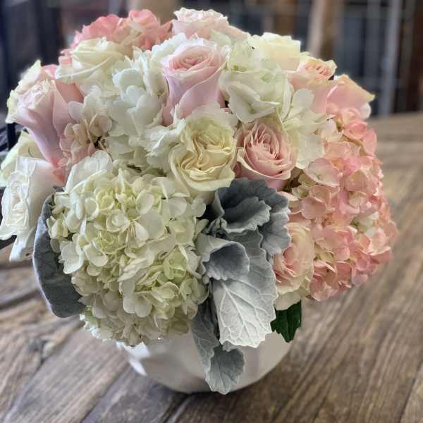 Bouquet of pale pink roses and white hydrangeas in a white container