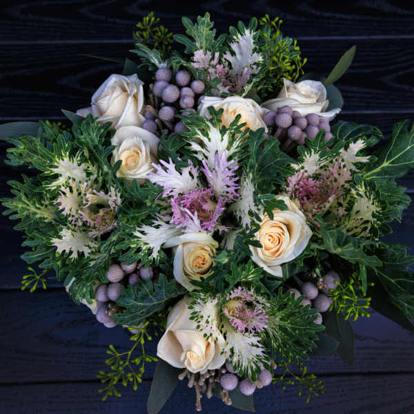 Bouquet of cream roses with purple accents and green foliage
