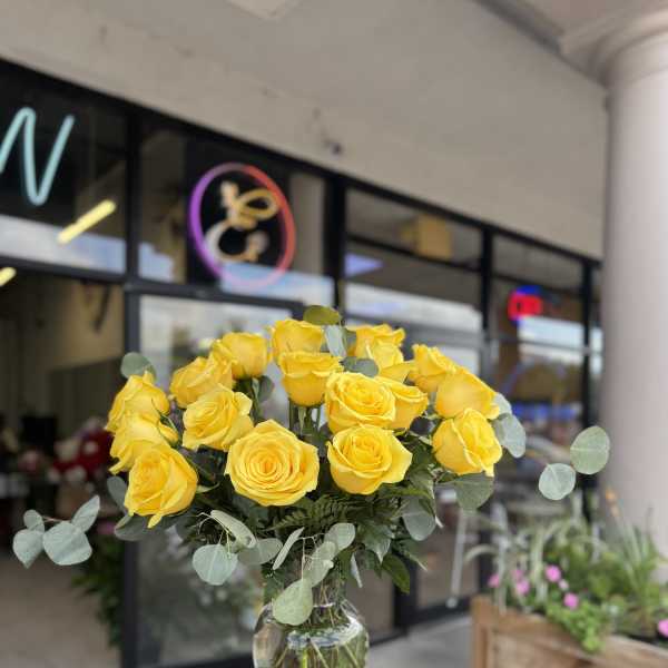 Yellow roses in a clear glass vase with eucalyptus