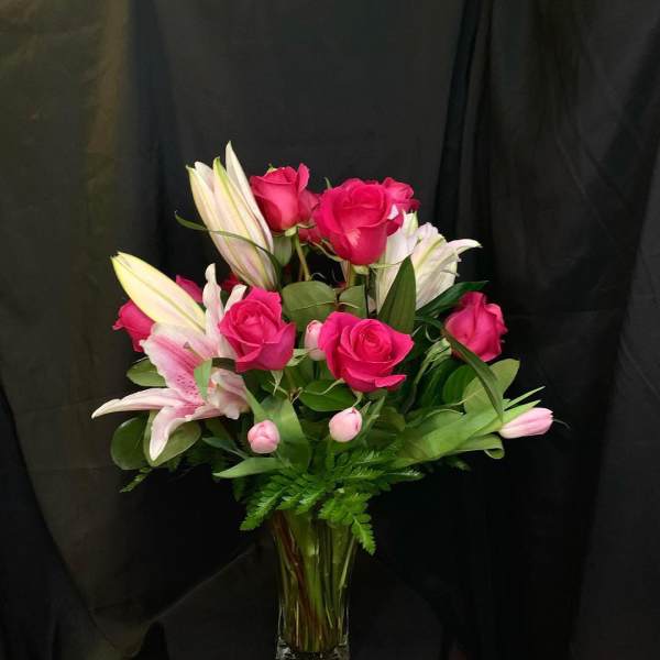 Pink roses and white lilies arranged in a clear glass vase