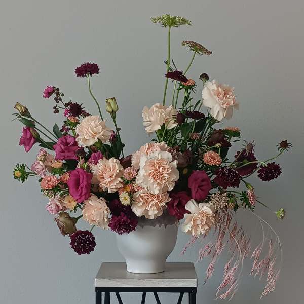Loose bouquet of pink and cream flowers in a white vase