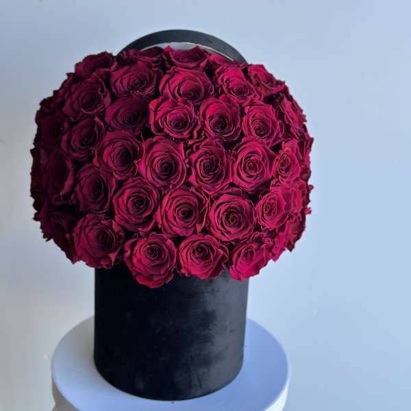 Round arrangement of deep pink roses in a black box