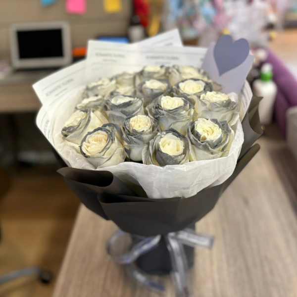 Bouquet of cream roses wrapped in black paper with a silver ribbon