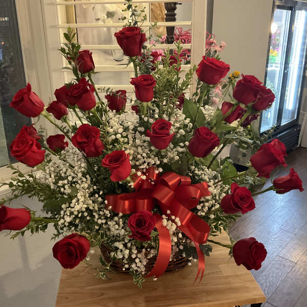 Basket arrangement of red roses with baby's breath and a red ribbon