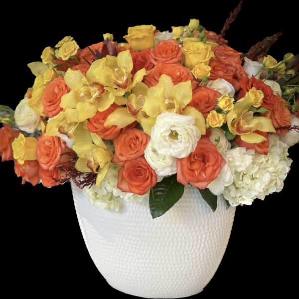 Orange and yellow roses with white blooms in a white textured vase