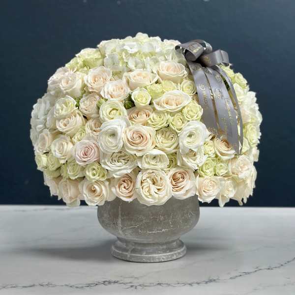 Cream rose bouquet in a gray vase with a silver ribbon