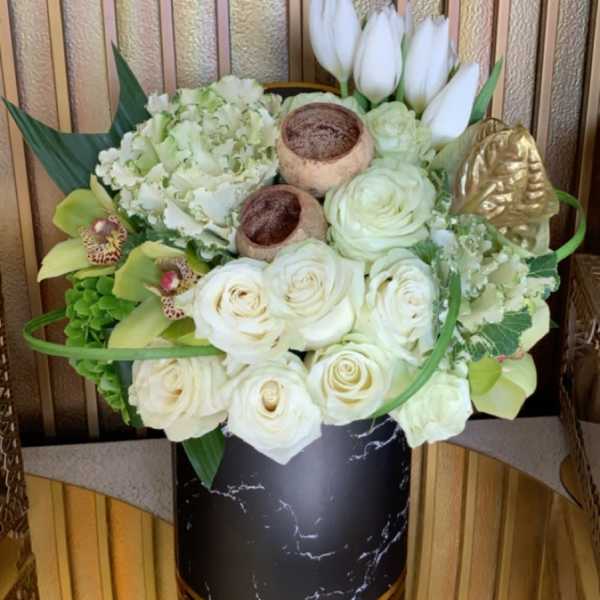White roses and tulips arranged in a black vase with gold accents