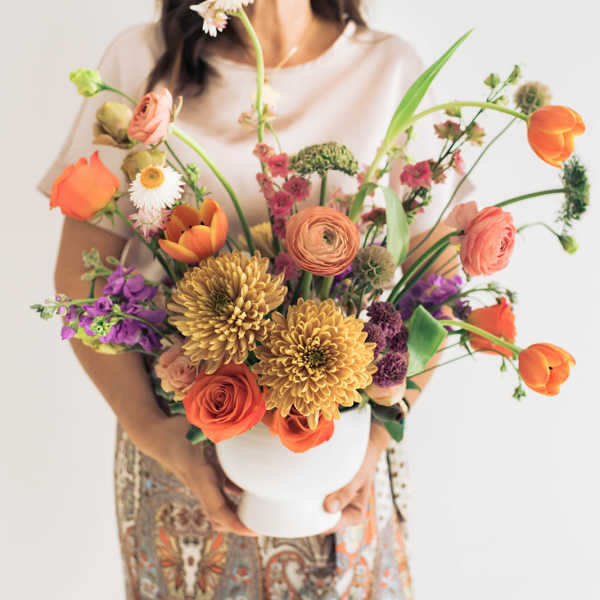 Mixed bouquet in a white vase with orange, pink, purple, and yellow flowers