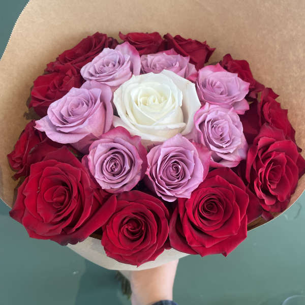 Bouquet of red, pink, and white roses wrapped in brown paper
