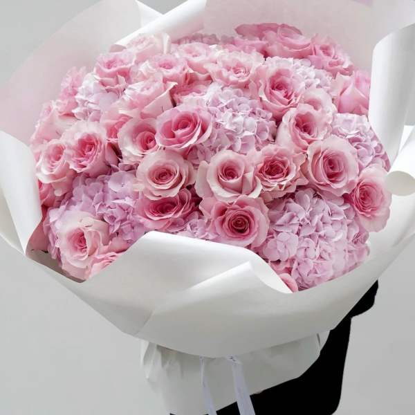Bouquet of pink roses and hydrangeas wrapped in white paper