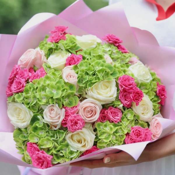 Bouquet of pink and white roses with green hydrangeas in pink wrapping