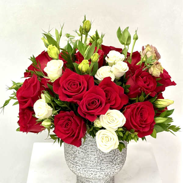 Arrangement of red and white roses with buds in a gray textured ceramic vase.