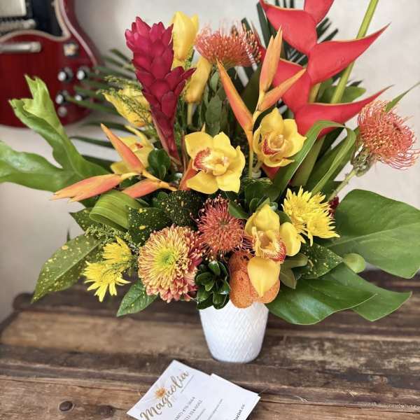 Tropical bouquet with red heliconia and yellow orchids in a white vase