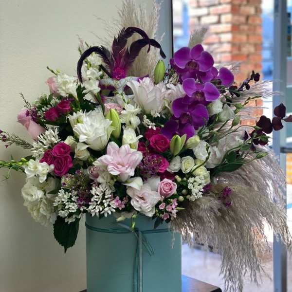Large bouquet of pink, white, and purple flowers in a blue hat box