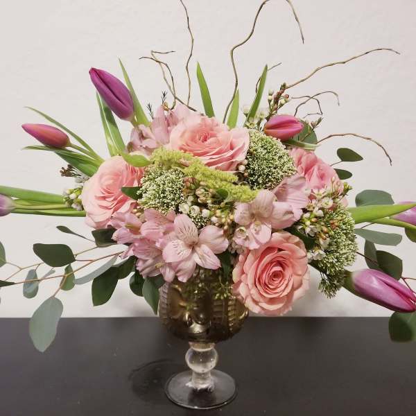 Pink roses and purple tulips in a gold goblet vase