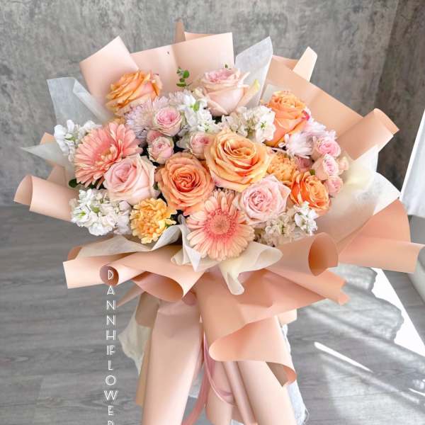 Peach and pink mixed bouquet with roses and daisies wrapped in blush paper