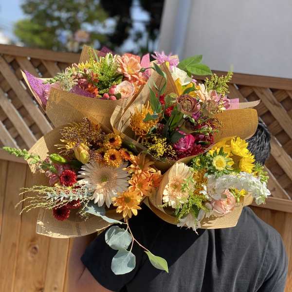 Person holding several colorful mixed flower bouquets wrapped in paper
