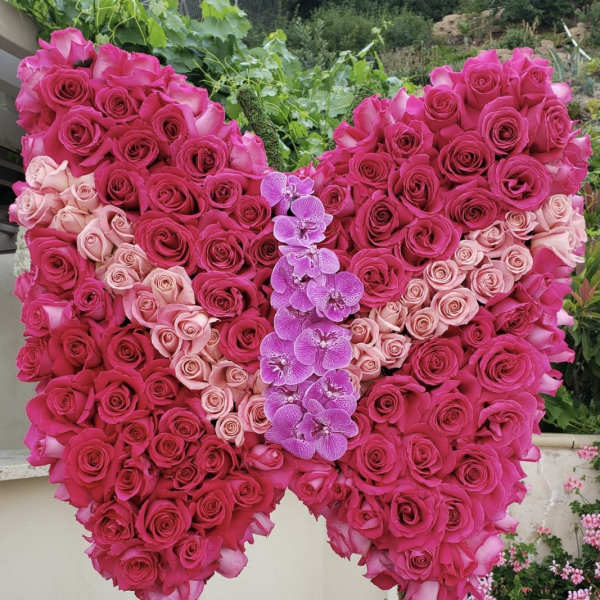 Heart-shaped rose arrangement with pink orchids in the center
