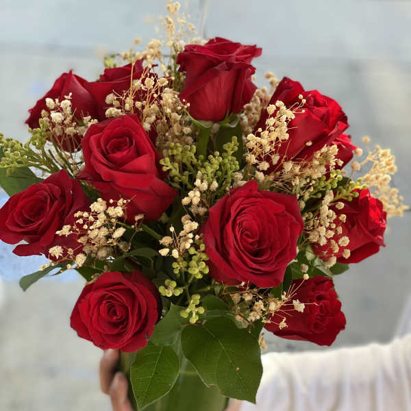 Bouquet of red roses with baby's breath in a green vase
