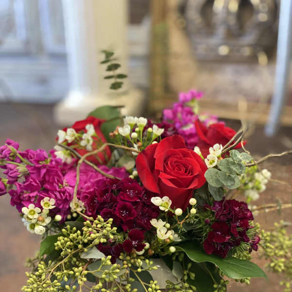 Red roses and magenta flowers arranged in a low vase