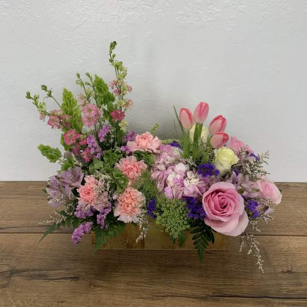 Pink and purple mixed flower arrangement in a rectangular wooden container
