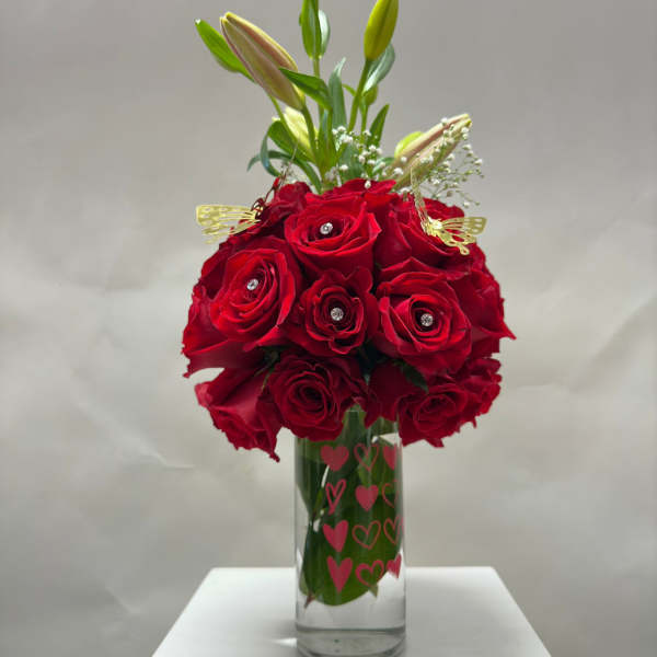 Red roses in a clear glass vase with lily buds and heart decals