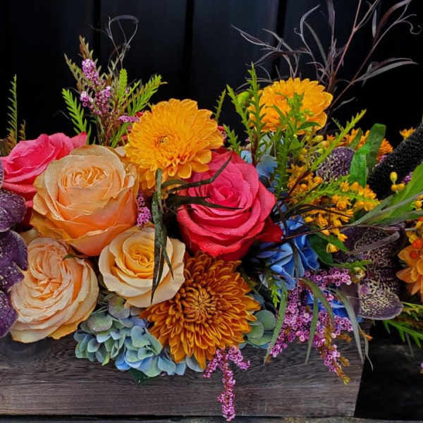 Colorful floral arrangement in a wooden box with roses and orchids