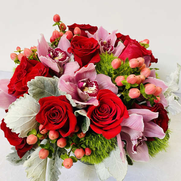 Bouquet of red roses and pink orchids with berry accents