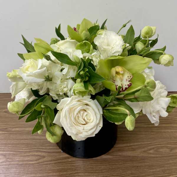 White and green floral arrangement in a black vase