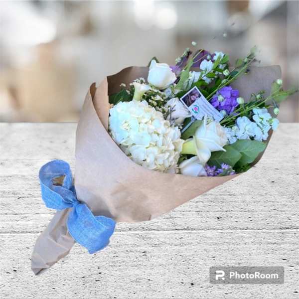 Wrapped bouquet of white and purple flowers tied with a blue ribbon