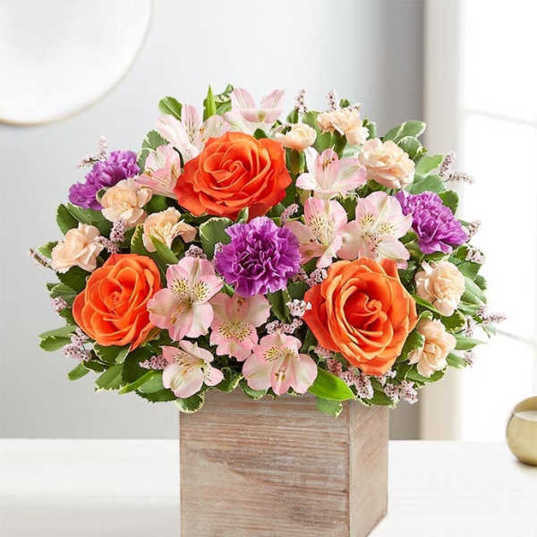 Bouquet of orange roses, pink alstroemeria, and purple carnations in a wooden box