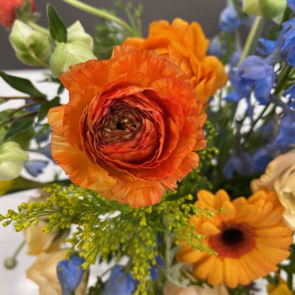 Bright mixed bouquet with orange ranunculus and blue flowers