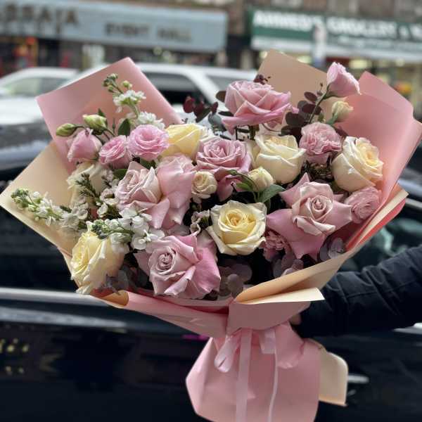 Bouquet of pink and cream roses wrapped in pastel paper