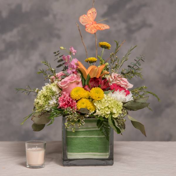 Mixed bouquet in a square glass vase with a butterfly topper