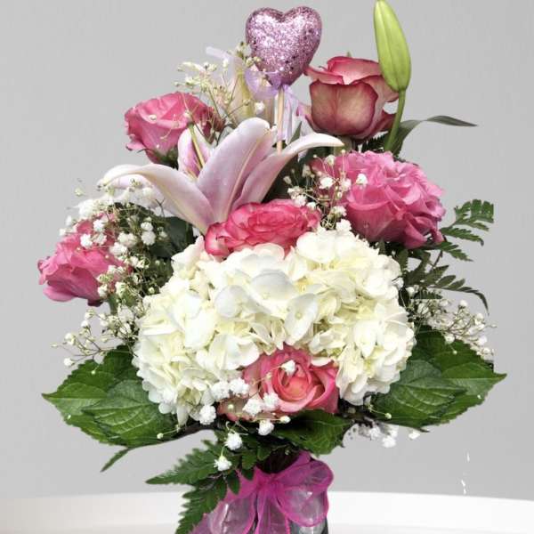 Pink and white bouquet with roses, hydrangea, and a lily in a vase
