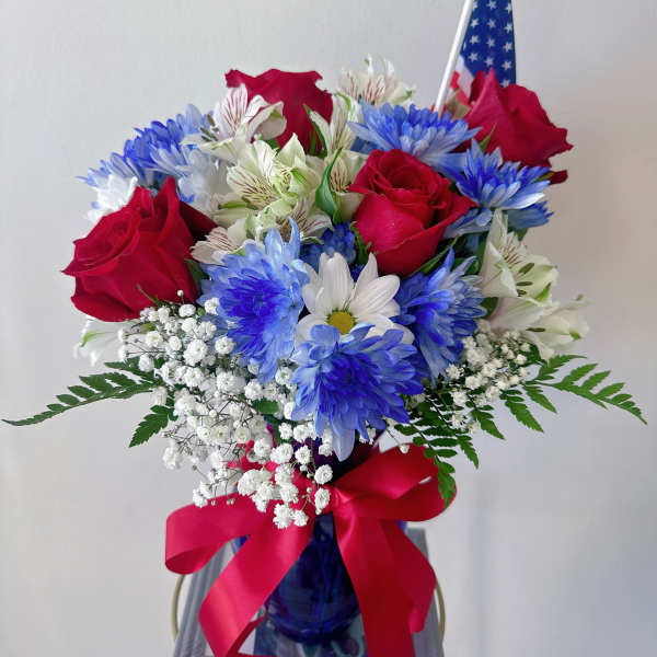 Bouquet of red roses, blue and white daisies, and baby's breath in a blue vase