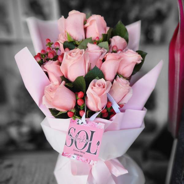 Pink rose bouquet wrapped in pale pink paper with a ribbon