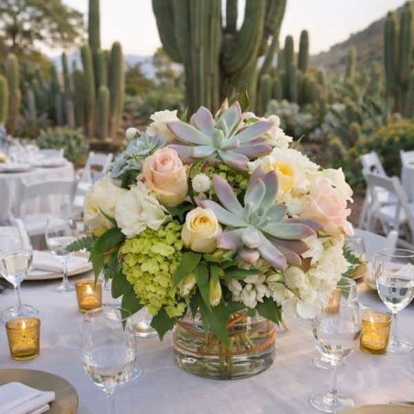 Low floral centerpiece in a glass vase on a set table outdoors