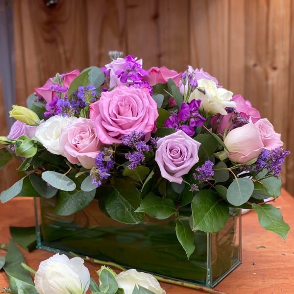 Pink and lavender roses arranged in a glass rectangular vase