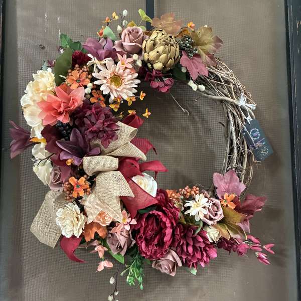 Floral wreath with pink, burgundy, and cream blooms on a twig base