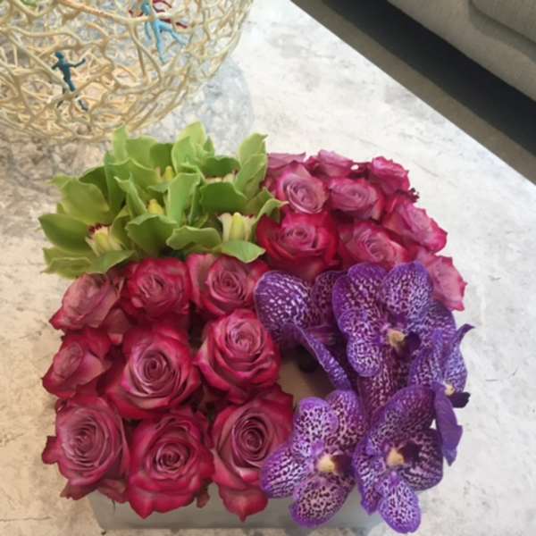 Pink roses and purple orchids arranged in a square box