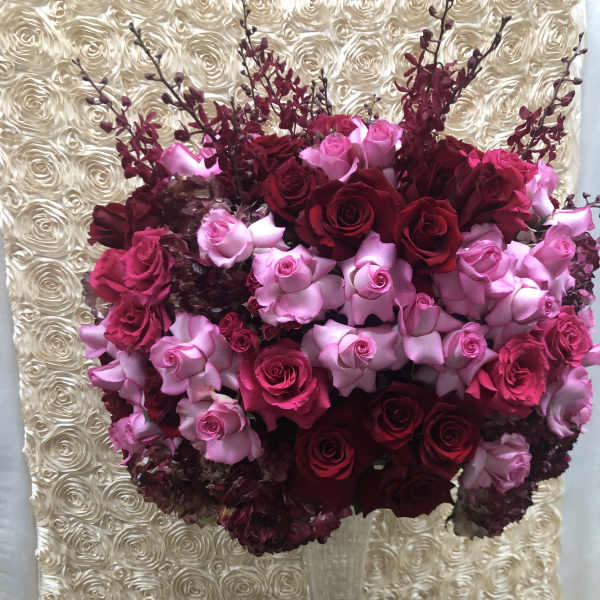 Tall bouquet of red and pink roses in a clear glass vase