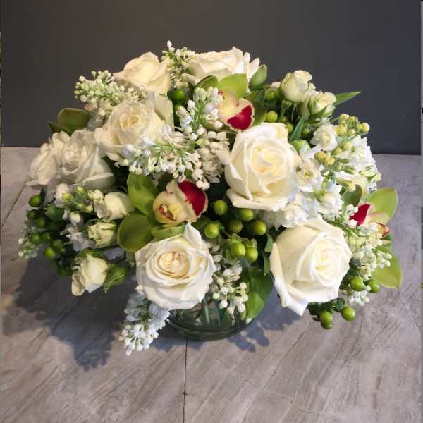 White roses and orchids arranged in a glass vase